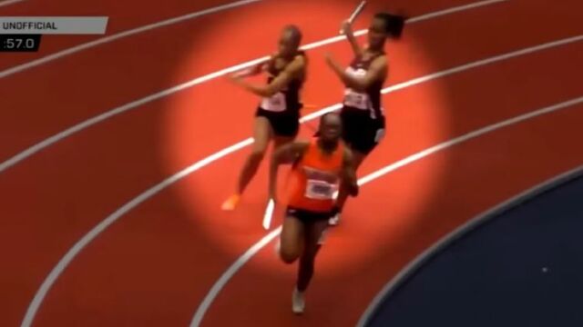 Докато състезателка по щафетно бягане изпреварва своя конкурентка в завоя